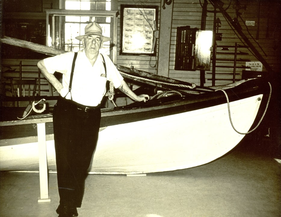 Photo: Archie Cartwright next to the whaleboat in Sanderson Hall, on the second floor of the Nantucket Whaling Museum. Credit: Nantucket Historical Association.