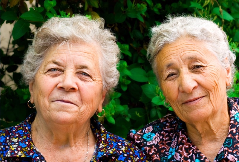 Photo: two elderly women in matching floral-print dresses.