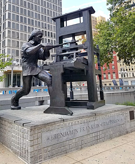 Photo: “Benjamin Franklin, Craftsman” by sculptor Joseph Brown, 1981. Credit: Wikimedia Commons.