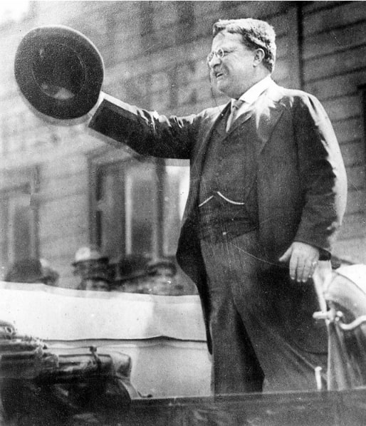 Photo: Theodore Roosevelt speaking from a car in Milwaukee on 14 October 1912, shortly before a gunman shot and wounded him in front of the Gilpatrick Hotel. Credit: Milwaukee Journal Sentinel; Wikimedia Commons.