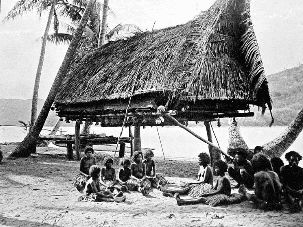a group and native house with human skulls, Mairy Pass, 1885. Mainland of British New Guinea in the distance. Credit: John William Lindt; Wikimedia Commons.