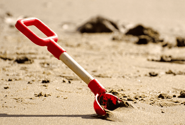 Photo: a shovel digging into the sand on a beach