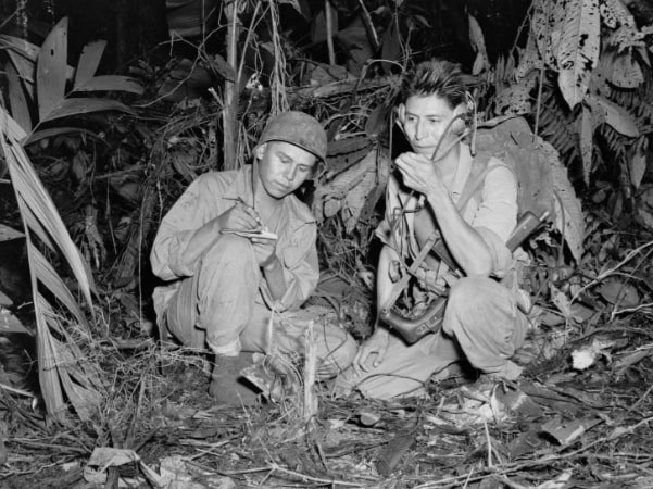 Photo: Corporal Henry Bake Jr. (left) and Private First Class George H. Kirk, Navajo Indians serving with a Marine Signal Unit, operate a portable radio set in a clearing they've just hacked in the dense jungle close behind the front lines during WWII. Credit: National Archives.