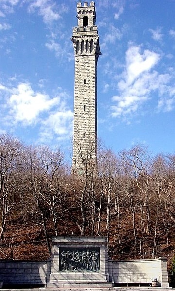 Photo: view of the Pilgrim Monument with the Mayflower Compact bas-relief by Cyrus Dallin below, as seen from Bradford Street, Provincetown, Massachusetts
