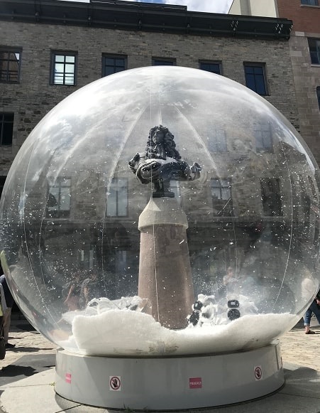 Photo: a life-size snow globe art installation by Lucie Bulot and Dylan Collins in Quebec City, Quebec, Canada, featuring a bust of Louis XIV. Credit: Gena Philibert-Ortega.