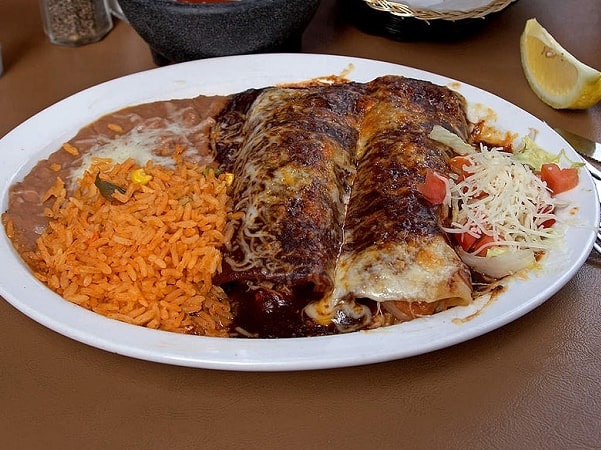 Photo: enchiladas with mole sauce, served with refried beans and Spanish rice. Credit: Jon Sullivan; Wikimedia Commons.