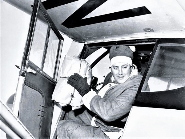 Photo: Edward Rowe Snow, the "Flying Santa," dressed for duty in his plane with one of the packages he is delivering. Courtesy of Dorothy Snow Bicknell, daughter of Edward Rowe Snow.