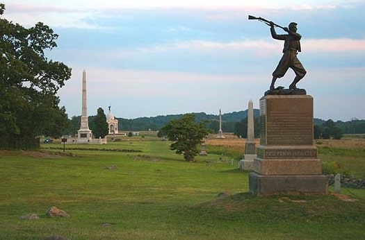 Photo: the high water mark on Cemetery Ridge with the monument commemorating the 72nd Pennsylvania Infantry Regiment at right and the Copse of Trees to the left. This photo looks south along the Ridge with Little Round Top and Big Round Top in the distant background. Credit: Robert Swanson; Wikimedia Commons.