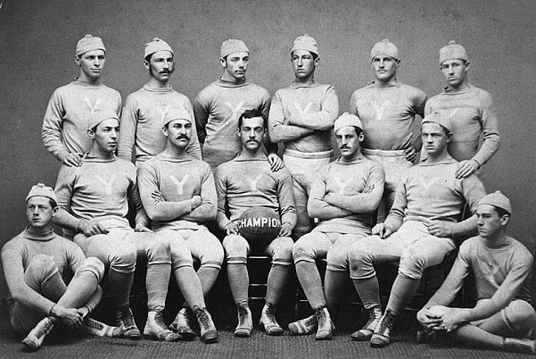 Photo: the 1876 Yale Bulldogs, national football champions. Walter Camp is standing with arms crossed. Credit: Wikimedia Commons.