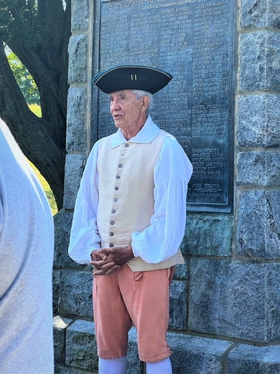 Photo: Avid Ross, a tour guide at Fort Griswold, standing in front of the marker “Defenders of Fort Griswold” in Fort Griswold Battlefield State Park, Groton, Connecticut. Credit: Friends of the Bill Memorial Library.