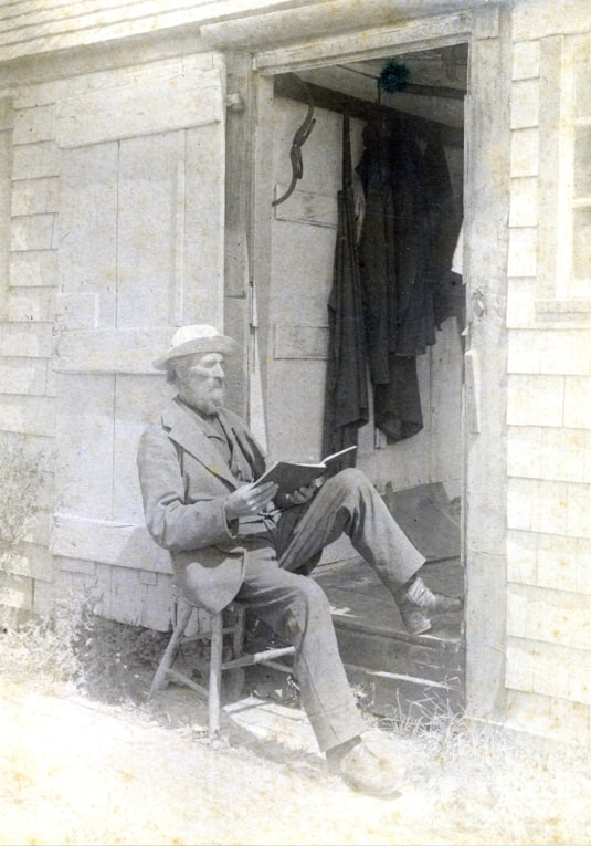 Photo: Captain Alden Hammond Adams seated outside, reading a book, at Adams Boat House on Steamboat Wharf, Nantucket. Courtesy of the Nantucket Historical Association.