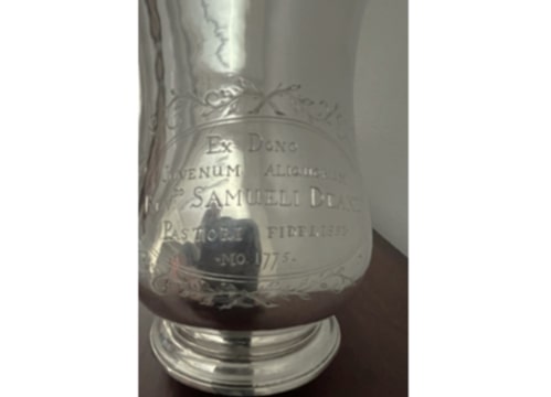 Photo: front view of the silver tankard gifted to Rev. Samuel Deane, 1775, showing the Latin inscription. Credit: First Parish Church, Portland, Maine.
