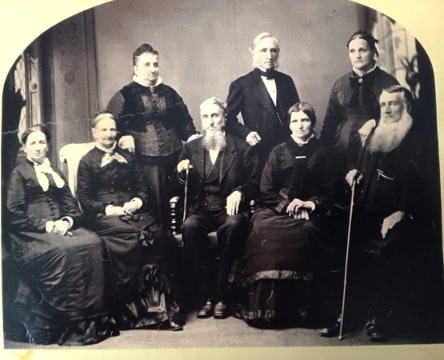 Photo: eight of the children of John Washington Cram and his wife Polly: (standing, left to right): Dr. Elizabeth Sanborn Cram Fenno (wife of Stephen Fenno); George Washington Cram (husband of Sarah Holden); and Elvira Catherine Cram Stevens (wife of John Nelson Stevens); (seated, left to right): Polly Cram Maloon (wife of Greenleaf Maloon); Nancy Cram Lane (wife of William Lane); Amos Cram (husband of Jane Sanborn Prescott); Mary Jane Cram Parsons (wife of Joseph Parsons); and Dr. John Cram (husband of Sarah Abbott Lane). Credit: Kathy Williams Curtis.