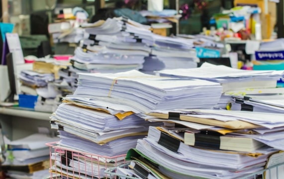 piles of paper needing organization. Credit: https://depositphotos.com/home.html