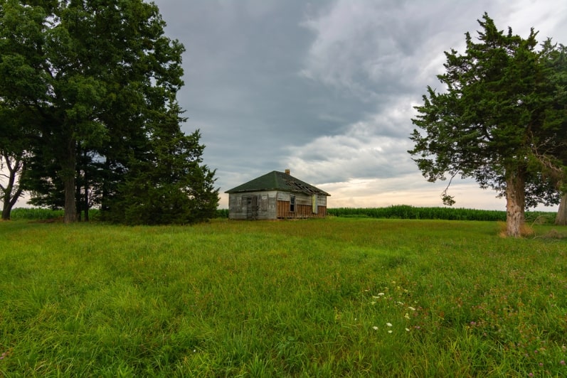 Photo: an old, abandoned farmhouse in a field.