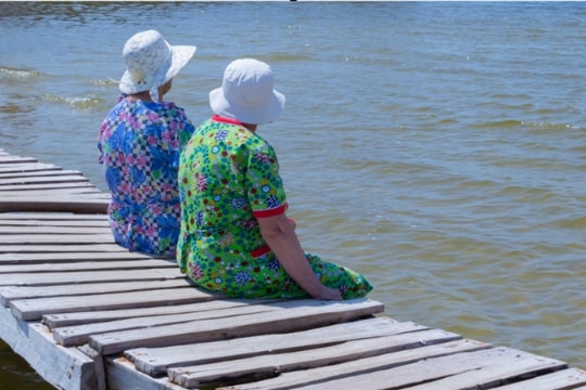 Photo: two grandmothers sitting on a dock together. Credit: https://depositphotos.com/home.html