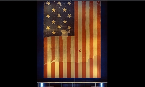 Photo: the large 15-star, 15-stripe "Star-Spangled Banner" flag that inspired Francis Scott Key's poem (which became the lyrics of the U.S. national anthem) when it flew above Fort McHenry in the 1814 Battle of Baltimore. Shown here on display at the Smithsonian's National Museum of History and Technology, around 1964. Credit: Smithsonian Institution Archives; Wikimedia Commons.